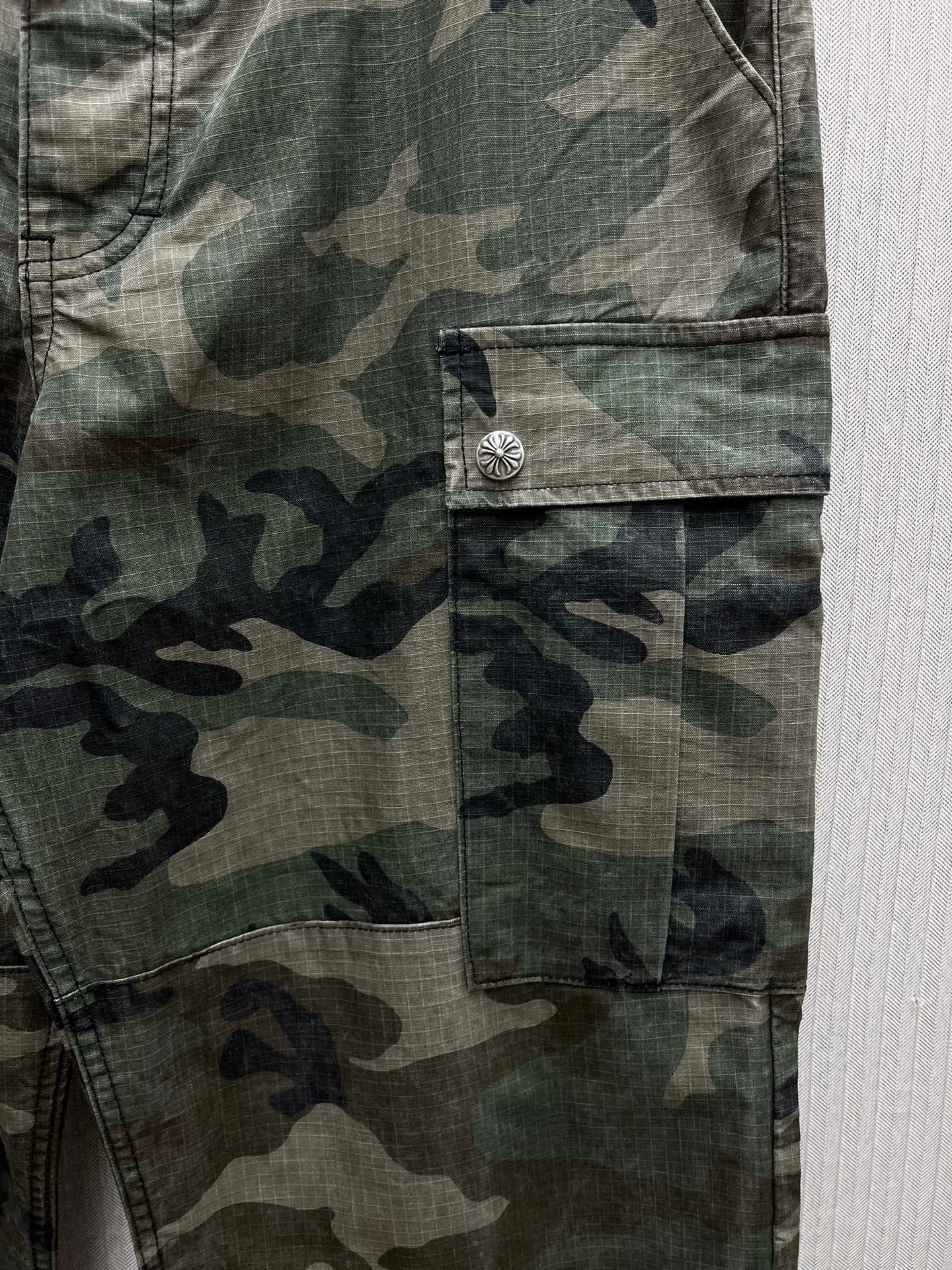 🅿️680 Crow Heart 25SS camouflage patchwork leather genuine antique silver overalls. The body fabric is custom-dyed with fully divided camouflage. The lining is CH jacquard lining. The minimum order is 1000 meters. There are 14 genuine antique silver hardware in the whole trousers. Half of the cost is in the hardware. The leather patchwork is made of imported lambskin. Hand-made edge turning method. The embroidery on the waist is imported Tajima machine. Precision embroidery. Size: 32.34.36